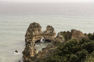 Portekiz 'deki Camilo Sahili' ndeki kayalık kayalıkların ve deniz yığınlarının manzarası. Engebeli kıyı şeridi dramatik kaya oluşumları ve kumlu bir plaja sahiptir..