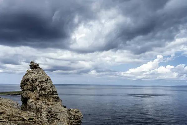 stock image A striking rocky formation at Cabo de Cavalleria, Menorca, with a backdrop of dramatic clouds over the serene Mediterranean Sea. Perfect for nature and travel themes.