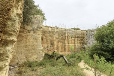 İspanya 'nın Menorca kentindeki Lithica Pedreres de s' Hostal 'daki antik taş ocaklarının büyüleyici manzarası etkileyici taş yapıları ve doğal yeşillikleri gözler önüne seriyor..