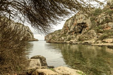 Cala Coves, Menorca 'da engebeli, kayalık bir körfez dramatik kayalıklar ve doğal mağaralar sergiliyor. Sakin, berrak sular bu eşsiz kıyı manzarasının vahşi ve el değmemiş güzelliğini arttırır..