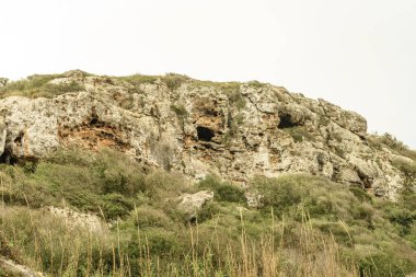 Cala Coves, Menorca 'daki antik nekropolis mağaralarının yakın çekimleri engebeli kaya oluşumlarını ve yemyeşil bitki örtüsünü gözler önüne seriyor. Bu tarihi mağaralar manzaraya gizemli bir cazibe katıyor..