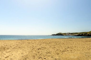 Menorca 'daki Cala Sa Mesquida' nın çarpıcı kıyı manzarası berrak mavi sular, kayalık kıyı şeridi ve parlak mavi bulutlar altında büyüleyici beyaz evler..