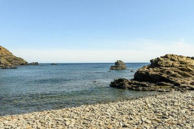 Menorca 'daki Cala Sa Mesquida' nın çarpıcı kıyı manzarası berrak mavi sular, kayalık kıyı şeridi ve parlak mavi bulutlar altında büyüleyici beyaz evler..