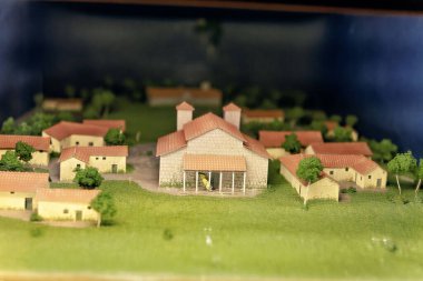 Kırmızı çatılı ve yeşil manzaralı küçük binalarla çevrili merkezi bir kilisenin yer aldığı tarihi bir köyün ayrıntılı ölçekli modeli..