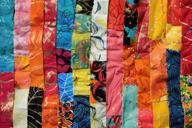 Değişik desenlere ve dokulara sahip renkli kumaşların canlı bir karışımı, canlı bir tekstil çeşitliliği sergiliyor..