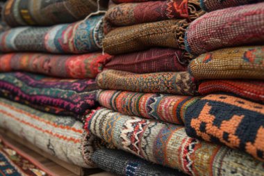 Bir pazarda karmaşık desenler sergilenen renkli katlanmış kumaş yığını, canlı renkler ve işçilik sergiliyor..