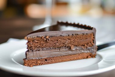 Beyaz tabakta birden fazla katmanı olan yozlaşmış bir çikolatalı kekin yakın çekimi..