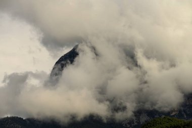 Dağ zirvesi kalın bulutlar tarafından gizleniyor, gizemli ve atmosferik bir manzara yaratıyor..