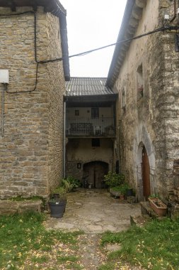 Huzurlu Barbenuta köyünde yeşilliklerle çevrili taştan binalarla dolu tuhaf bir ara sokak..