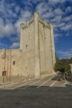 The iconic Castillo de Torija, featuring robust stone walls and cylindrical towers, standing tall against a vivid blue sky and surrounded by greenery. clipart