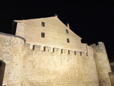 Burgo de Osma 'nın ortaçağ taş duvarlarının arkasındaki tarihi tuğla binanın gece manzarası, güzelce aydınlatılmış..