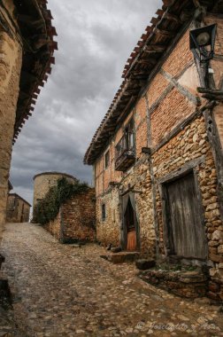 İspanya 'nın Soria kentindeki tarihi bir köyde, taştan duvarları olan geleneksel yarı ahşap evler kaldırım taşından bir cadde üzerindedir..