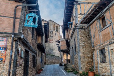 İspanya 'nın Soria kentindeki bir köyde tarihi bir taş kiliseye giden orta çağ ağaçlandırılmış evlerle dolu sevimli bir sokak..