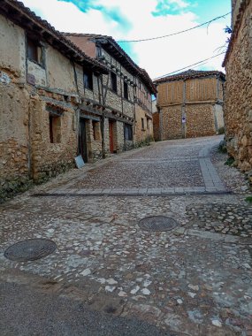 İspanya 'nın Soria kentindeki tarihi bir köyde, taştan duvarları olan geleneksel yarı ahşap evler kaldırım taşından bir cadde üzerindedir..