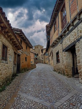 İspanya 'nın Soria kentindeki tarihi bir köyde, taştan duvarları olan geleneksel yarı ahşap evler kaldırım taşından bir cadde üzerindedir..