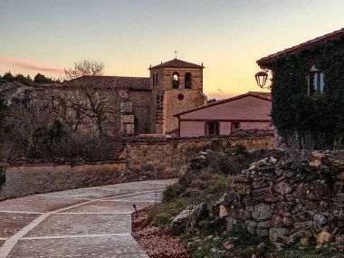 Calataazor 'daki tarihi taş binaların ve kırsal duvarların üzerinde günbatımının altın renklerinde yıkanan bir ortaçağ çan kulesi yükseliyor..