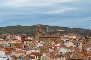 Arnedo, La Rioja, İspanya 'nın panoramik manzarasında tarihi bir kasaba, terasotta çatılı evler, tepede bir ortaçağ kalesi ve bulutlu bir gökyüzü altında bir kilise sergileniyor..