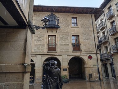 Laguardia, İspanya 'daki tarihi taş bina, kemerli kapılar, ahşap balkonlar ve cephesinde süslü bir demir saat var..