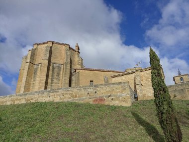 İspanya, San Vicente de la Sonsierra 'daki ortaçağ şatosu ve kilisesi, yeşil tepeler ve bulutlu gökyüzünün altındaki ağaçlarla çevrili..
