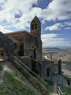 Santa Maria Belediye Başkanı Kilisesi 'nin çan kulesi ve San Vicente de la Sonsierra, İspanya' daki ortaçağ taş duvarları güneş ışığıyla bulutlu bir gökyüzünün altında..