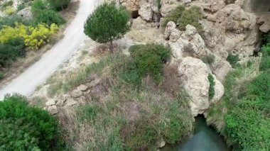 Yeşil ve kayalarla çevrili gizli bir şelalenin insansız hava aracı görüntüsü.