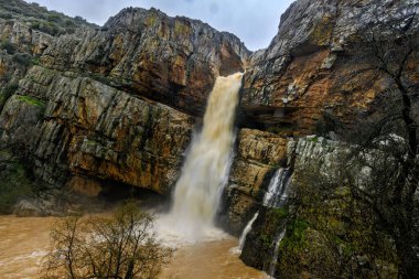 Cascada de la Cimbarra 'nın çarpıcı uzun bir görüntüsü. Suyun kayalık uçurumlarda sorunsuzca aktığı, yemyeşil bitki örtüsü ve dramatik manzaralarla çevrili..