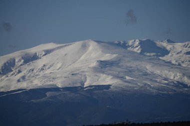 İspanya, Sierra Nevada 'nın nefes kesici manzarası, karla kaplı uçsuz bucaksız zirvelerini, derin mavi gökyüzünü ve manzara üzerindeki dramatik bulut oluşumlarını gözler önüne seriyor..