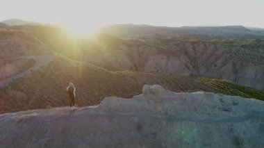 Dağın tepesinde seyahat kamerası olan bir kız manzaranın fotoğraflarını çekiyor..