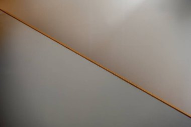 Kapalı bir duvarda, temiz geometriyle ışığı ve gölgeyi ayıran basit çapraz çizgi.