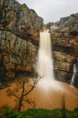 Cascada de la Cimbarra 'nın çarpıcı uzun bir görüntüsü. Suyun kayalık uçurumlarda sorunsuzca aktığı, yemyeşil bitki örtüsü ve dramatik manzaralarla çevrili..