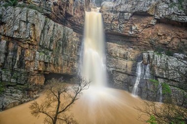 Cascada de la Cimbarra 'nın çarpıcı uzun bir görüntüsü. Suyun kayalık uçurumlarda sorunsuzca aktığı, yemyeşil bitki örtüsü ve dramatik manzaralarla çevrili..