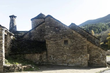 Fanlo köyünde kayrak çatılı taştan evler, yemyeşil vadiler ve parlak mavi gökyüzünün altında yükselen dağlar..