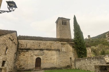 Tanınmış bir çan kulesi ve küçük bir mezarlığı olan Roma taştan kilisesi, dağ manzaralı huzurlu bir kırsal alana kurulmuş..