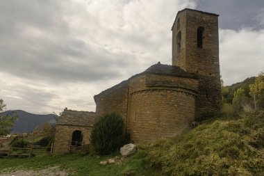 Çan kulesi, kırsal mimarisi ve tepeli huzurlu kırsal manzarası olan küçük bir Romen taş kilisesi..