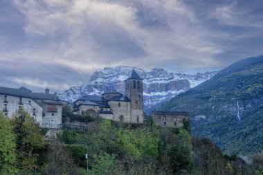 Taş bir kilise ve yakınlardaki binalar karla kaplı muhteşem bir zemin ve canlı yeşil bir vadi üzerine kurulmuş..
