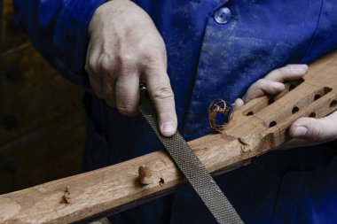 Zanaatkar ahşap gitar boynunu ahşap bir aletle şekillendiriyor.
