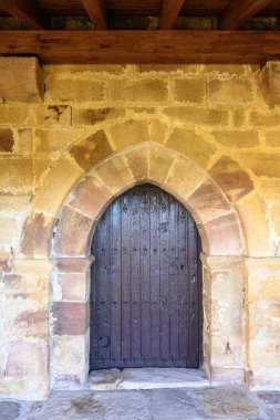 Palencia İspanya 'da taş kemerli ve koyu ahşap kapılı Roma kilisesi kapısı.