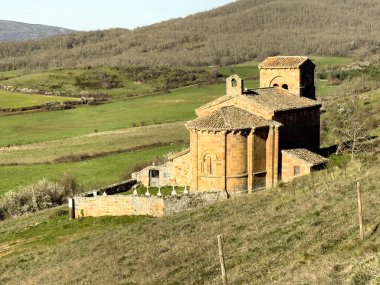 Taş duvarları, kırmızı fayanslı çatısı ve Palencia kırsalında kurulu çan kulesi olan tarihi Roma kilisesi..