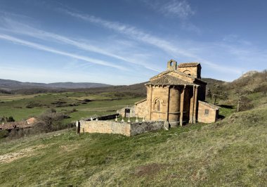 Taş duvarları, kırmızı fayanslı çatısı ve Palencia kırsalında kurulu çan kulesi olan tarihi Roma kilisesi..