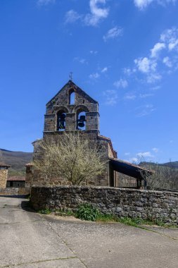 Parapetu 'da çan gable ve çiçek açan ağacı olan antik taş kilise.