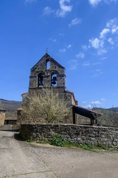 Parapetu 'da çan gable ve çiçek açan ağacı olan antik taş kilise.
