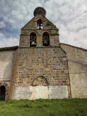 İspanya 'nın kırsal kesimlerinde gökyüzü bulutlu ve yeşil çimenleri olan eski taş kilise..
