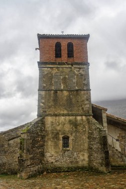 Taştan ve tuğladan yapılmış eski bir kilisede kırsal bir köyde önemli bir çan kulesi var..