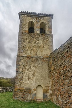 Vahşi bitki örtüsüyle çevrili tarihi taş kilise kulesi..
