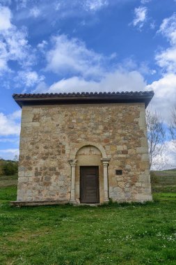 İspanya 'da bulutlu gökyüzünün altında yeşil kırsal bir arazide taş duvarlar ve maymunlarla dolu Romanca bir keşiş..