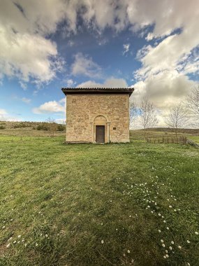 İspanya 'da bulutlu gökyüzünün altında yeşil kırsal bir arazide taş duvarlar ve maymunlarla dolu Romanca bir keşiş..
