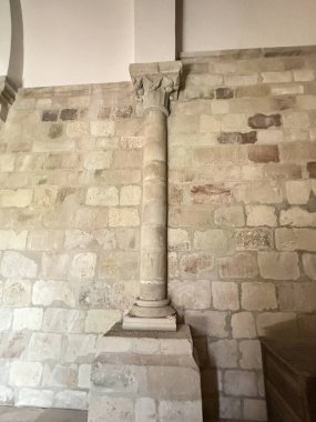 Antik kilisenin duvarına karşı düz taş sermayeli tek bir Roma sütunu.