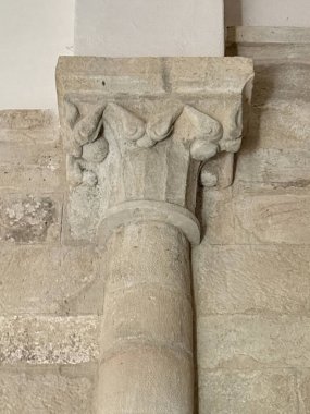 Antik kilisenin duvarına karşı düz taş sermayeli tek bir Roma sütunu.