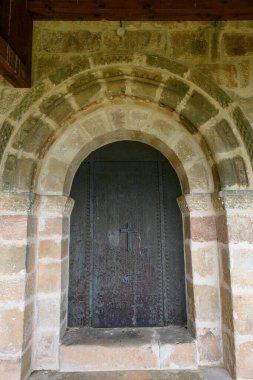 Ahşap çatının altında taş kemerli ve eski ahşap kapılı Roma kilisesi girişinin ayrıntıları.