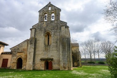 Santa Eufemia de Cozuelos Kilisesi 'nin taş ön cephesi. İspanya' nın Olmos de Ojeda şehrinde çan gable ve kemerli kapıları var..